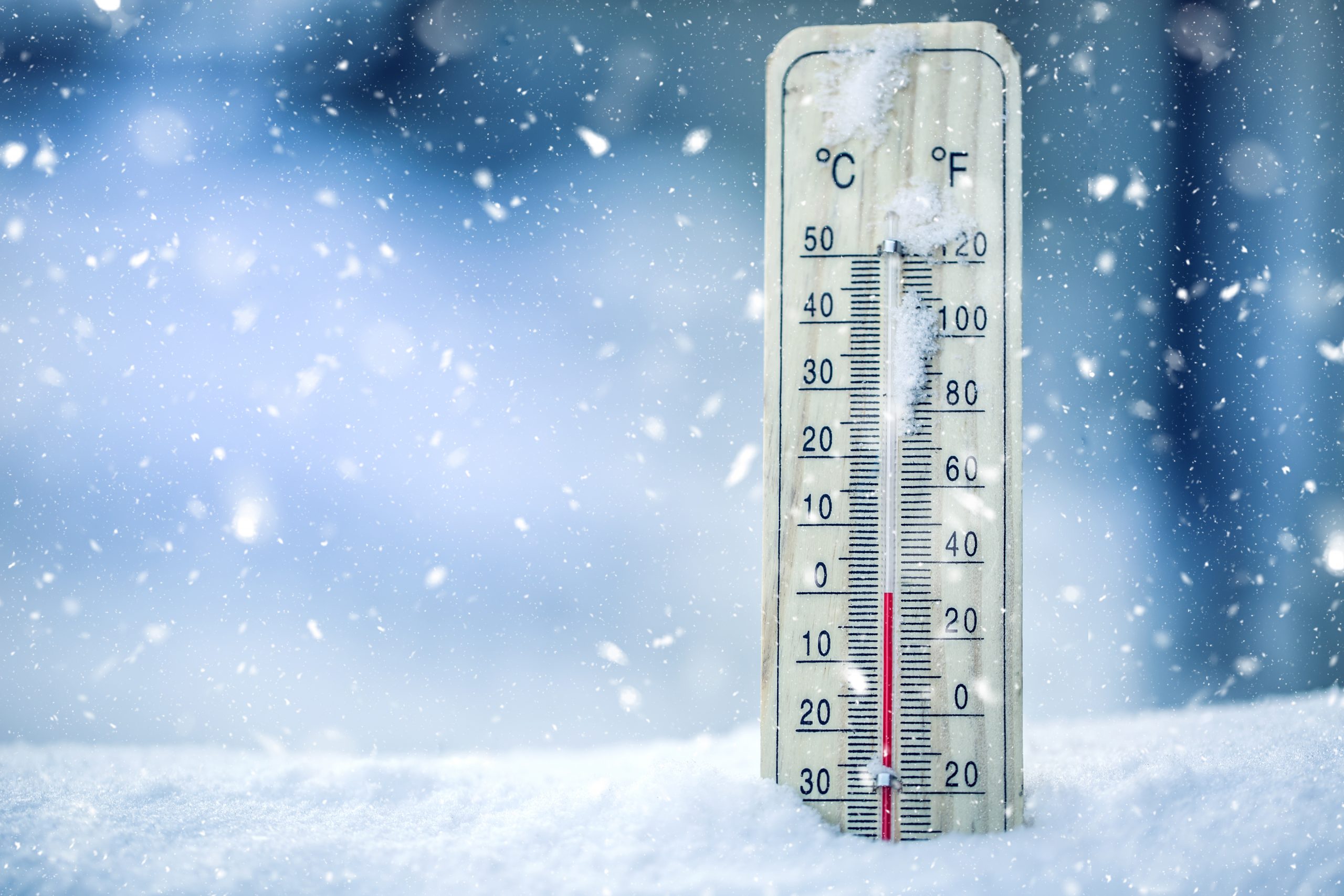 Thermometer on snow shows low temperatures - zero. Low temperatures in degrees Celsius and fahrenheit. Cold winter weather